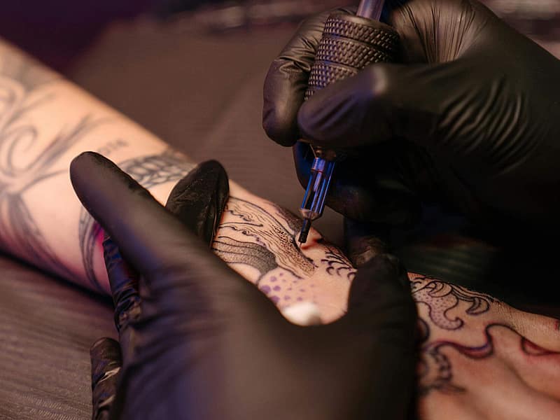 Tätowierer skizziert ein Cover-up-Design über einem alten Tattoo