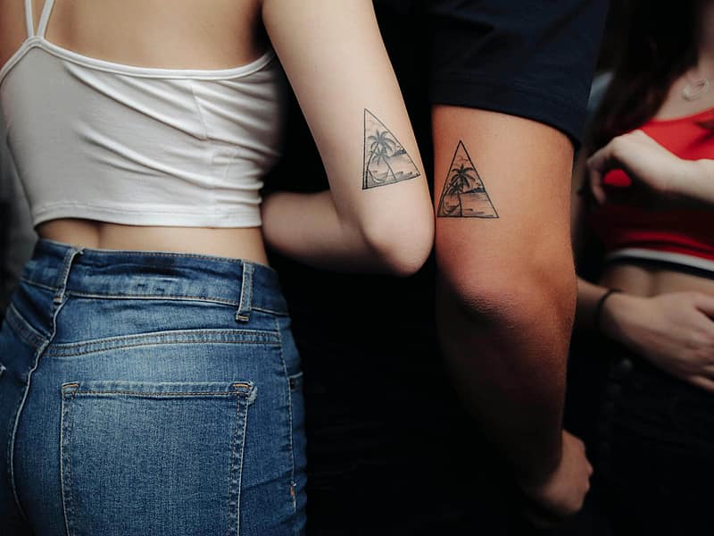 Zwei Freunde vergleichen kleine passende Tattoos auf ihren Armen